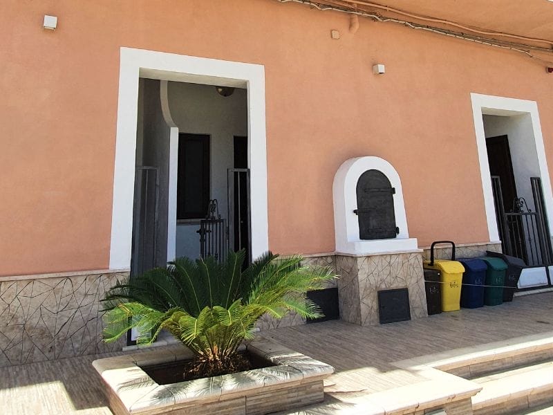 Un edificio rosa con davanti una pianta in vaso - Casa Vacanze a Lampedusa.