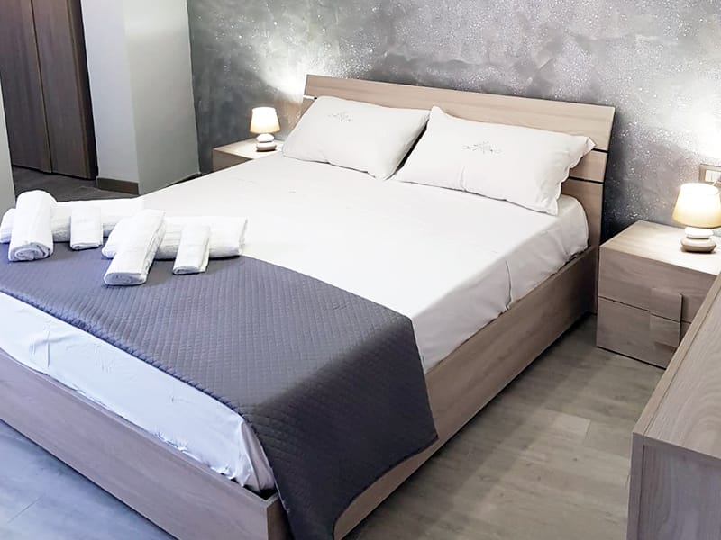 Uno o più letti in una stanza con lenzuola e asciugamani bianchi in una case vacanze in affitto a Lampedusa.