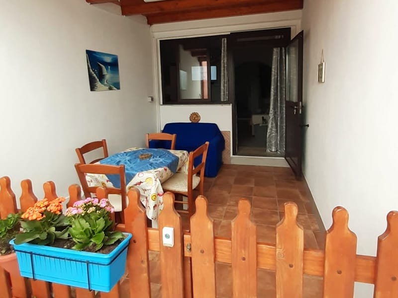 Una casa vacanza a Lampedusa che offre un balcone con staccionata in legno e un accogliente tavolo e sedie.