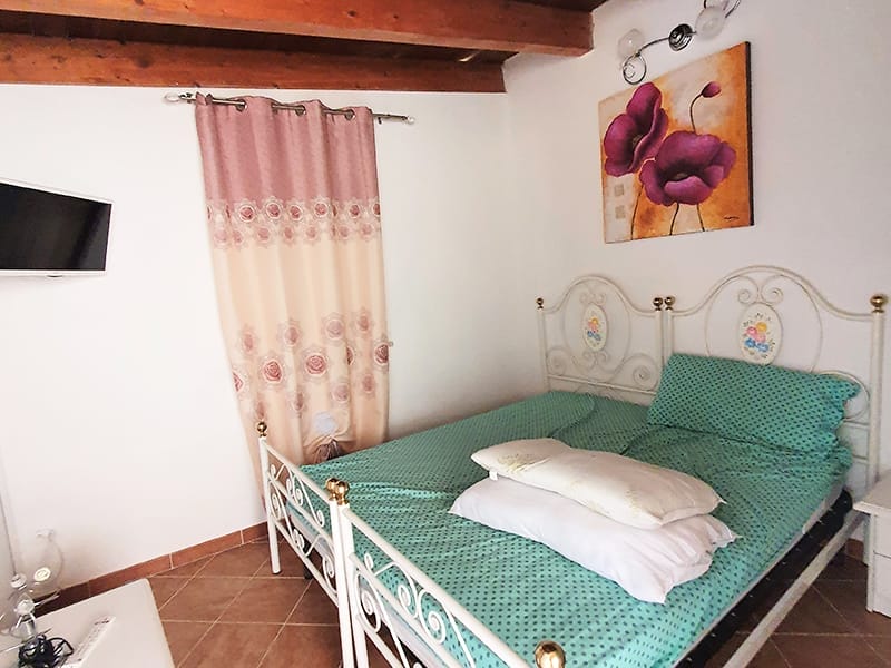 Un letto in una stanza con un quadro alla parete, perfetta per soggiorni vacanza a Lampedusa.