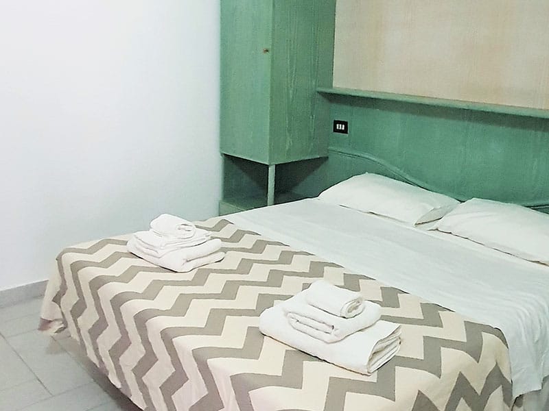 Una casa vacanza a Lampedusa con uno o più letti in una stanza con una parete verde.