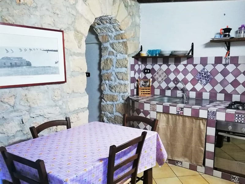 Una piccola cucina con tavolo e sedie a Lampedusa.