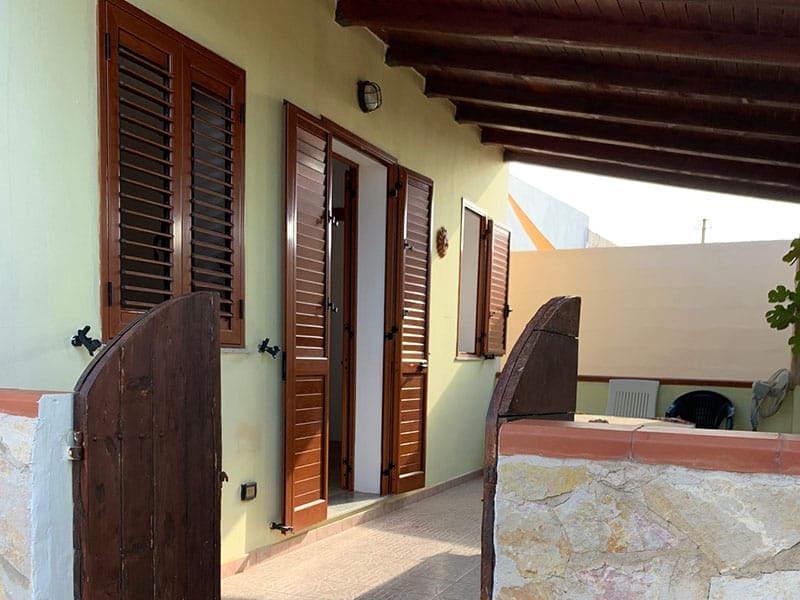 Una porta di legno con persiane marroni in una casa a Lampedusa.