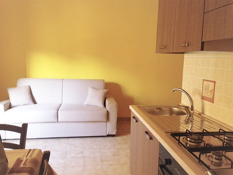 Un'accogliente cucina con divano e piano cottura, perfetta per una vacanza rilassante a Lampedusa.
