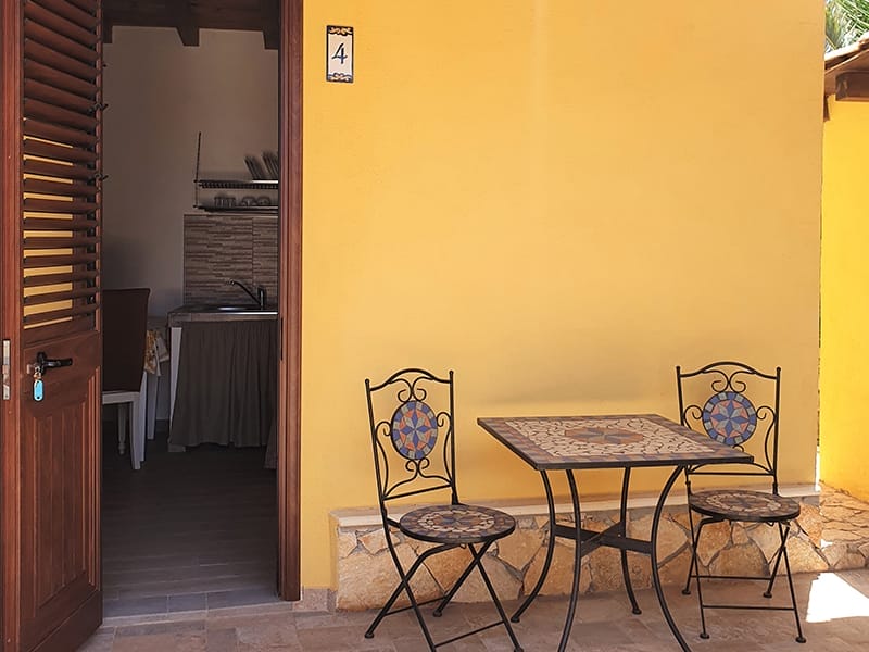 Un Residence con un patio arredato con tavolo e sedie davanti ad un muro giallo.
