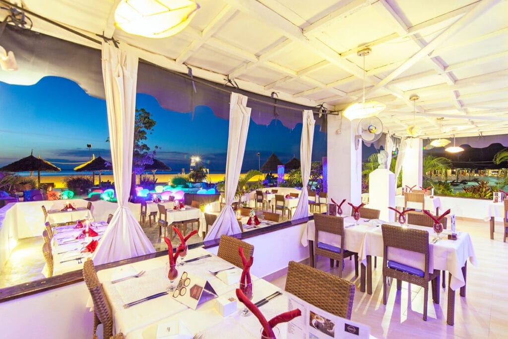 Un ristorante con tavoli e sedie bianchi che offre offerta viaggio a zanzibar alpitour.