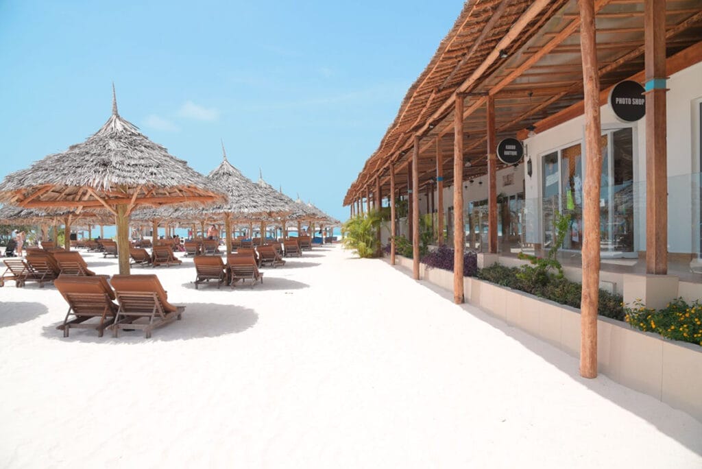 Una spiaggia con sedie a sdraio e ombrelloni di paglia. Goditi la vacanza perfetta al Bravo Premium Kendwa Beach, dove potrai rilassarti sulle sedie a sdraio sotto splendidi ombrelloni di paglia. Realizza il viaggio dei tuoi sogni