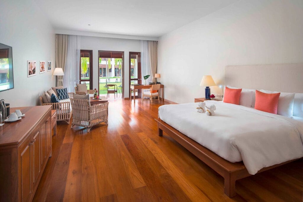 Una camera da letto con un letto grande e pavimenti in legno nel resort Bravo Premium Khao Lak in Tailandia.