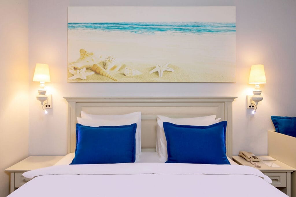 Un letto bianco con cuscini blu e un dipinto sul muro garantiscono tranquillità.