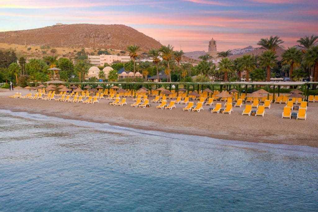 Offerta viaggio a Bodrum in Turchia per una spiaggia con sedie e ombrelloni.