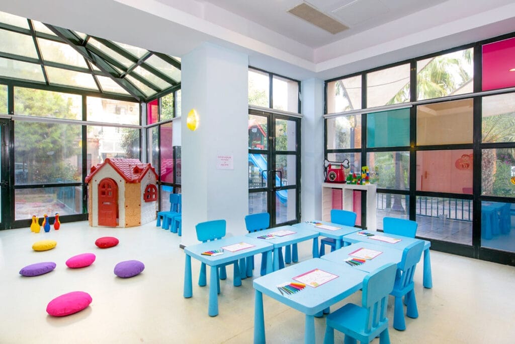 Una colorata cameretta per bambini con tavoli e sedie.