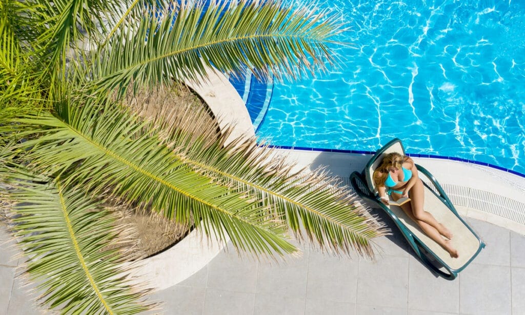 Una donna si gode un'esperienza serena a bordo piscina su una poltrona, abbracciando l'atmosfera deliziosa e la tranquillità.