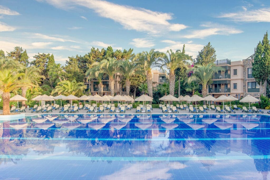 Un'invitante piscina con lettini, ombrelloni e un'allettante offerta viaggio a Bodrum in Turchia.