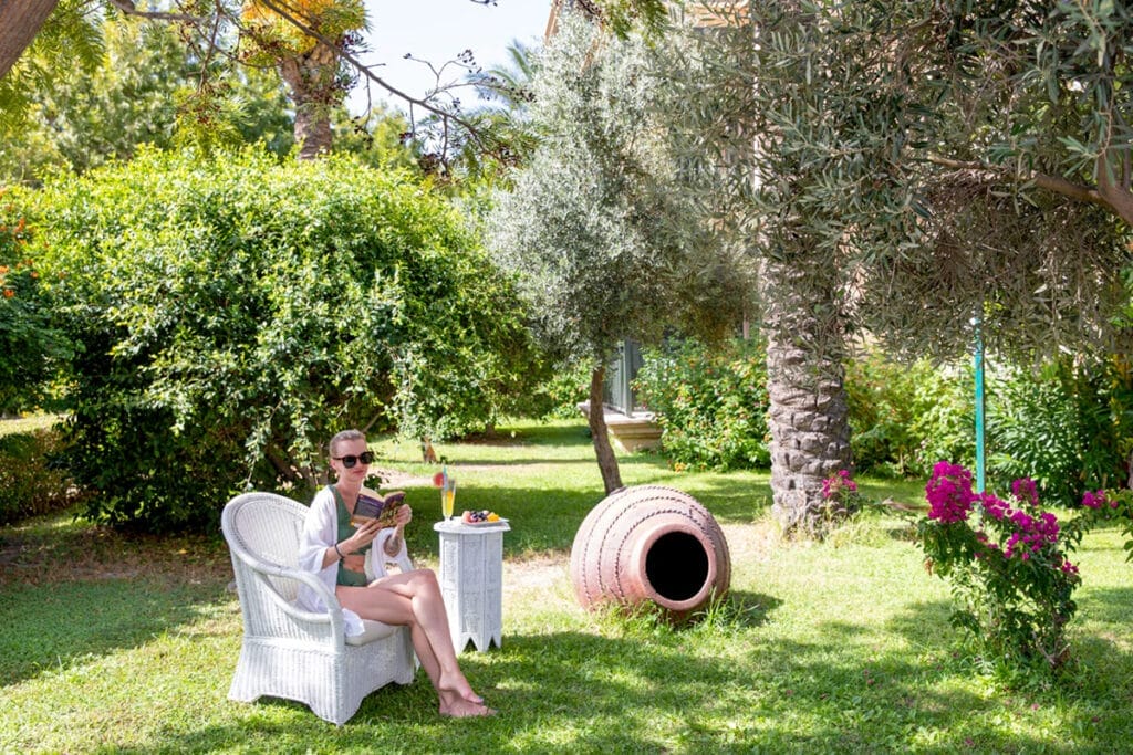 Una donna che si gode un momento di pace su una sedia tra le bellissime piante di un giardino.