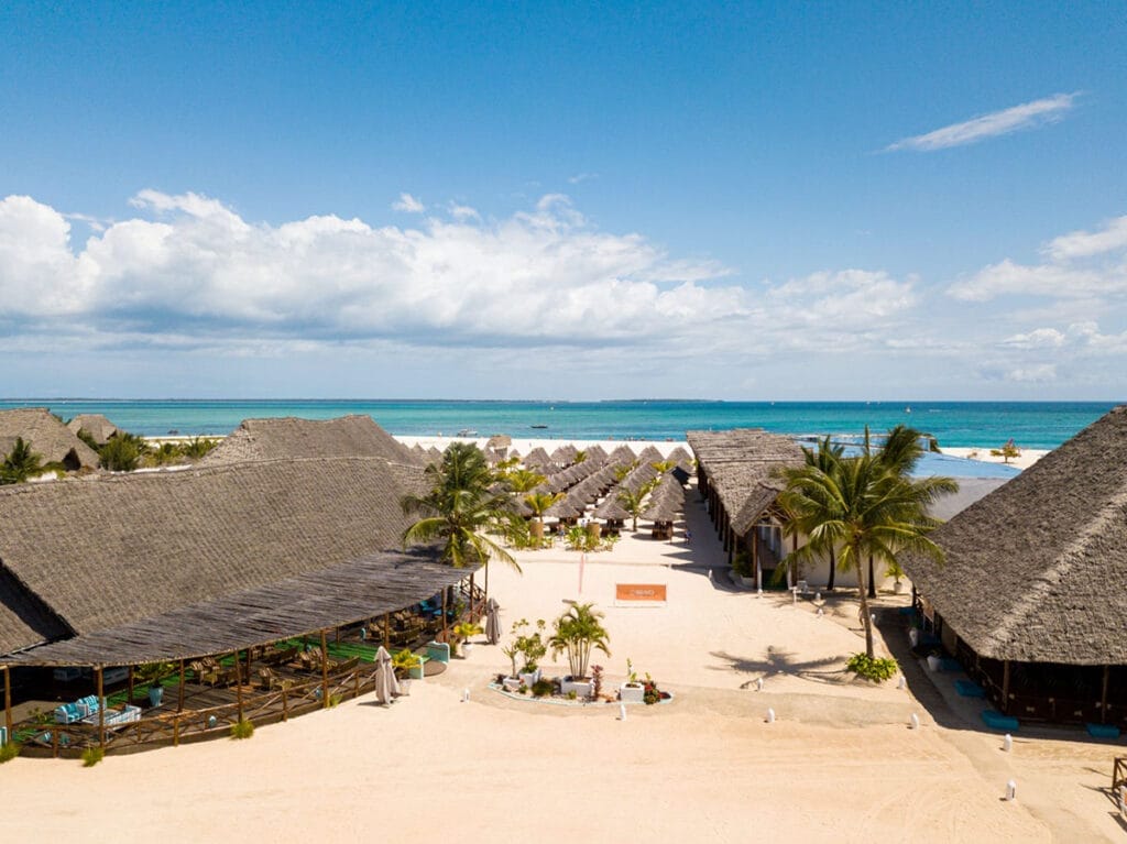 Una veduta aerea di un resort sulla spiaggia con capanne dal tetto di paglia che offre un'offerta viaggio a Zanzibar Alpitour e Bravo Premium Kendwa Beach experience.