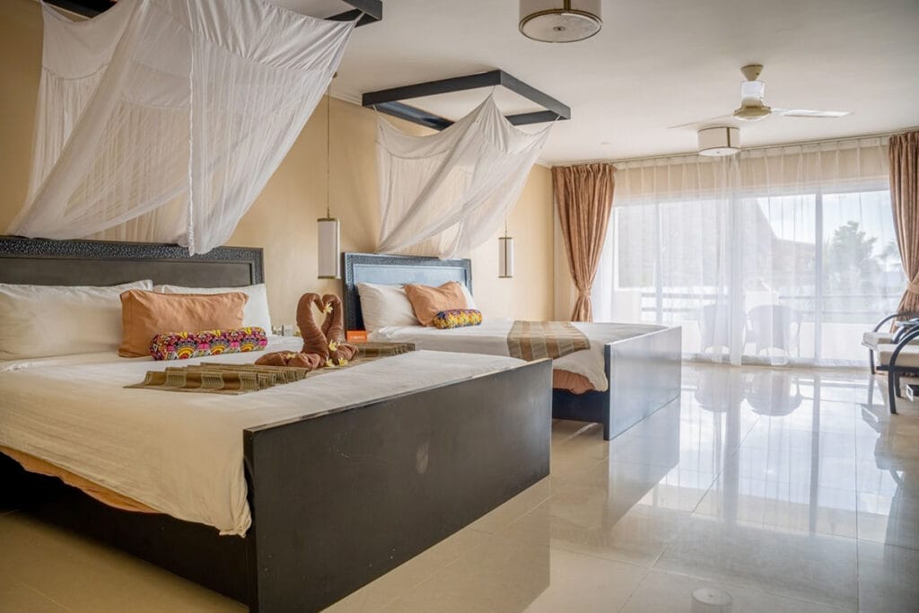Una camera con due letti e un baldacchino al Bravo Premium Kendwa Beach.