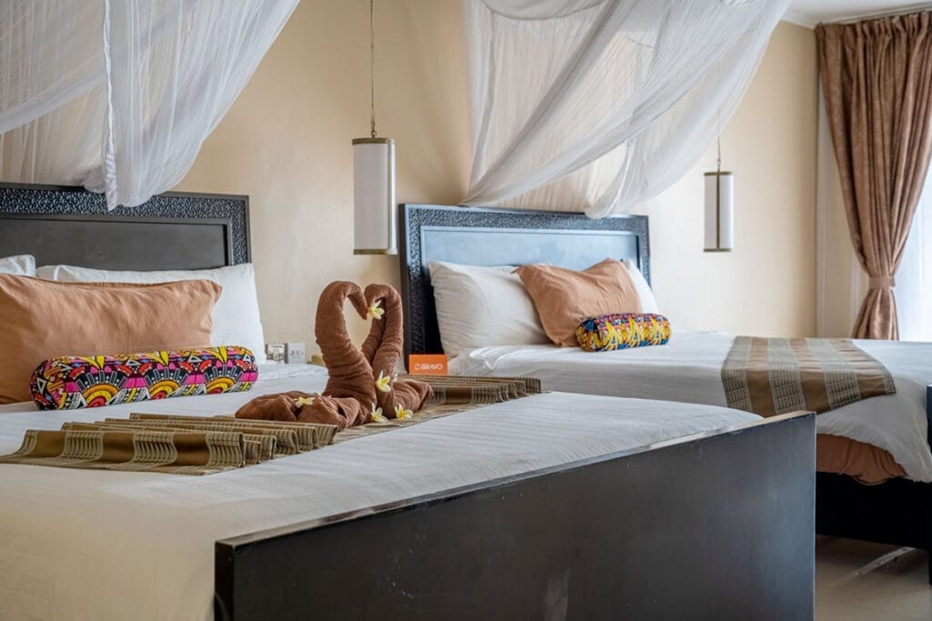 Una camera con due letti e baldacchino, disponibile per un'offerta viaggio a Zanzibar Alpitour. La camera si trova presso il resort Bravo Premium Kendwa Beach.