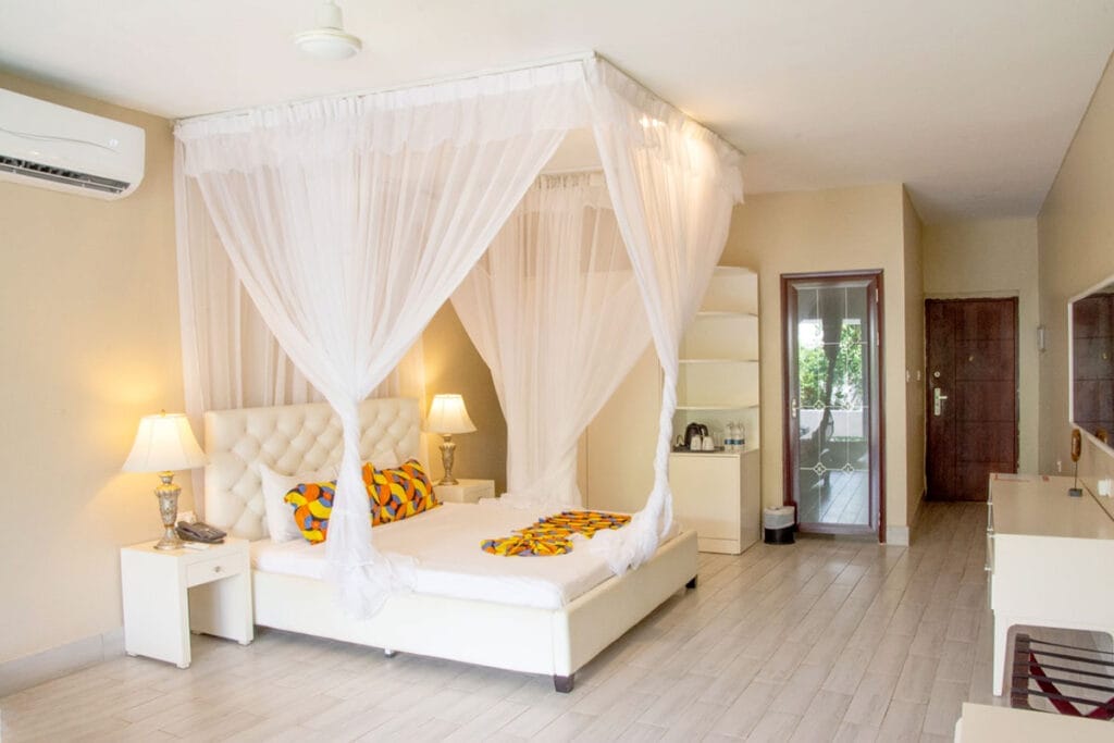 Un letto a baldacchino bianco in una stanza del Bravo Premium Kendwa Beach.