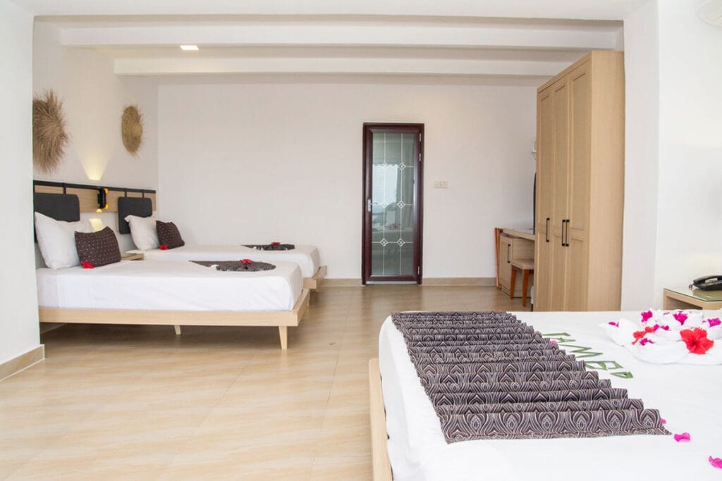 Una camera con due letti e fiori sul letto. Questa camera fa parte del pacchetto offerta viaggio a zanzibar alpitour, organizzato da SBS Viaggi.