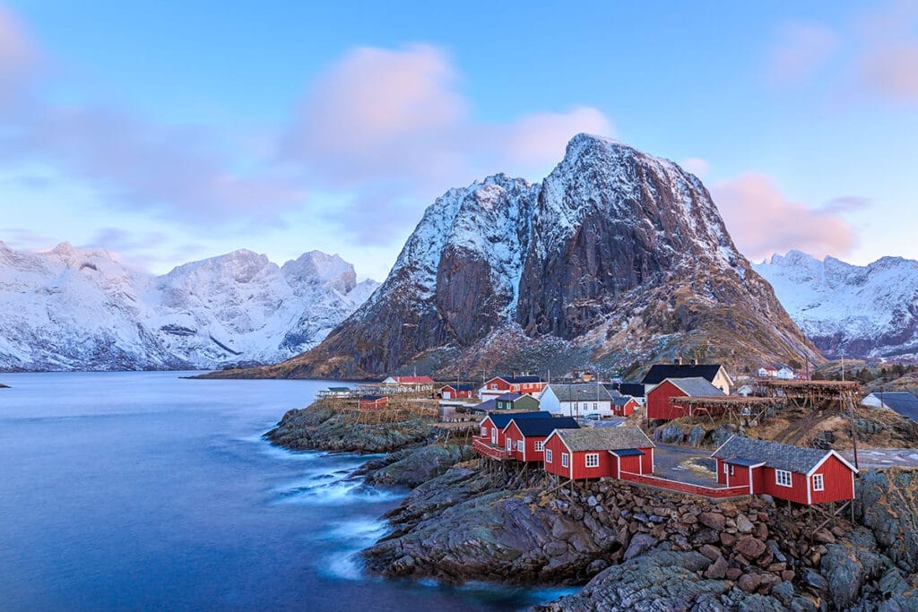 Una casa rossa si trova sulla cima di una montagna vicino a uno specchio d'acqua in Norvegia.