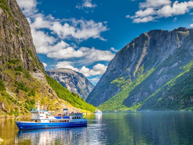 Una barca blu che naviga nelle acque della Norvegia a mezzanotte.