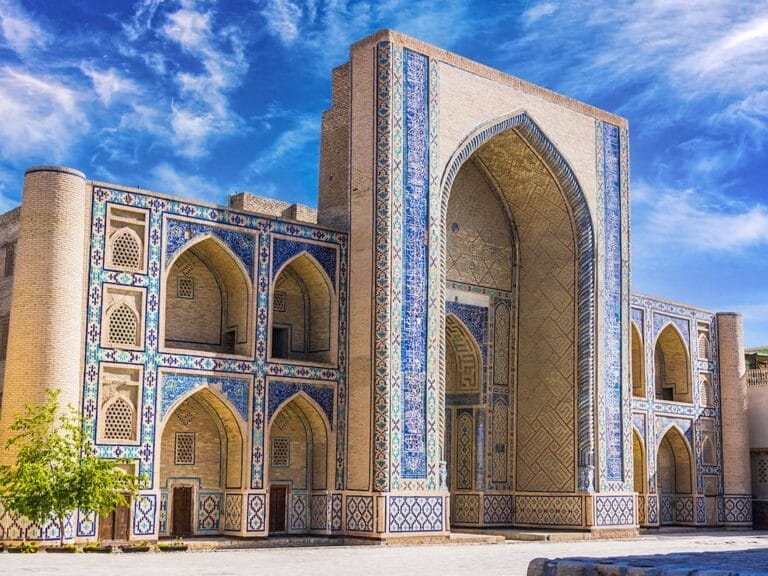 Un edificio Classico piastrellato in bianco e blu nel mezzo di un cortile in Uzbekistan.