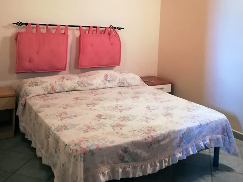 Una coperta rosa adorna un letto in una residenza della Casa Vacanze à Lampedusa.