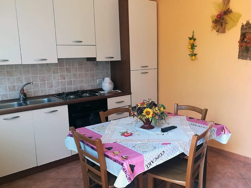 Una piccola cucina con tavolo e sedie in un residence Casa Vacanze a Lampedusa.
