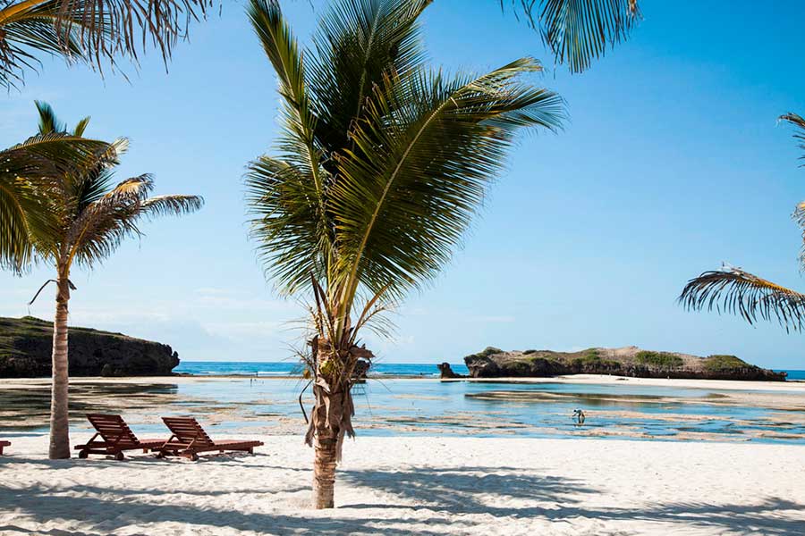 Una spiaggia di sabbia bianca con palme sullo sfondo, situata in un Seaclub Resort.