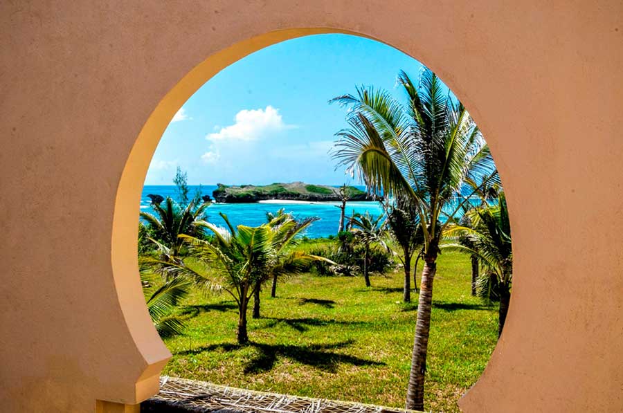 Un pittoresco arco al 7 Islands Resort, che offre una vista mozzafiato sull'oceano e sulle palme ondeggianti.