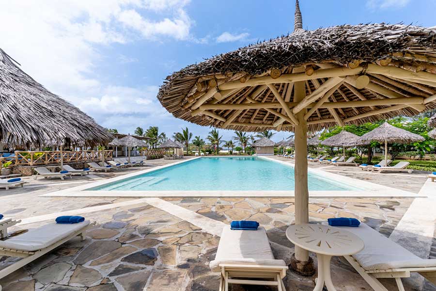 Il 7 Islands Resort dispone di una splendida piscina ornata da un tetto di paglia e completata da invitanti sedie.