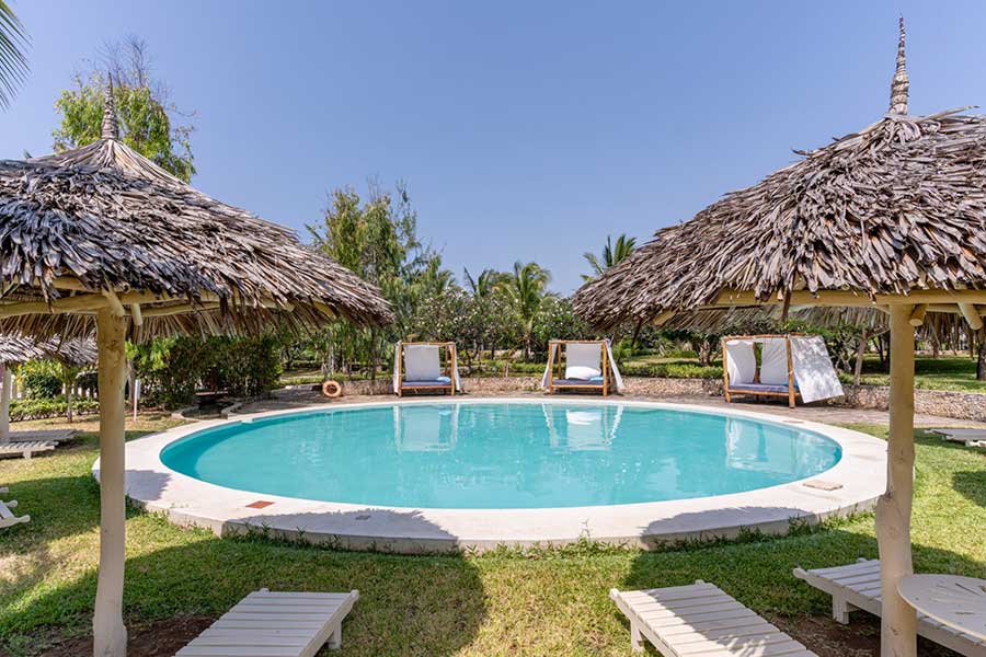 Una piscina con ombrelloni di paglia e sedie a sdraio al 7 Islands Resort.