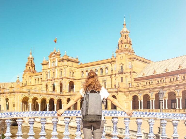 Una donna con uno zaino davanti a un edificio a Siviglia, Spagna, mentre si gode un tour dell'Andalusia offerto da SBS Viaggi.