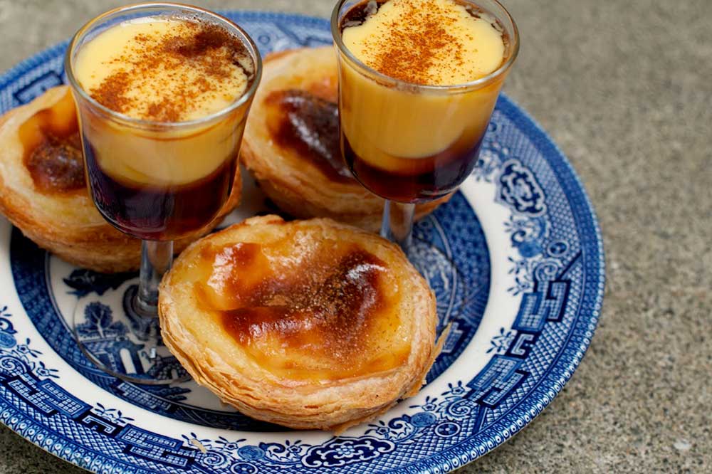 Un tour espresso del Portogallo che mostra un piatto blu e bianco con sopra tre deliziosi dessert.