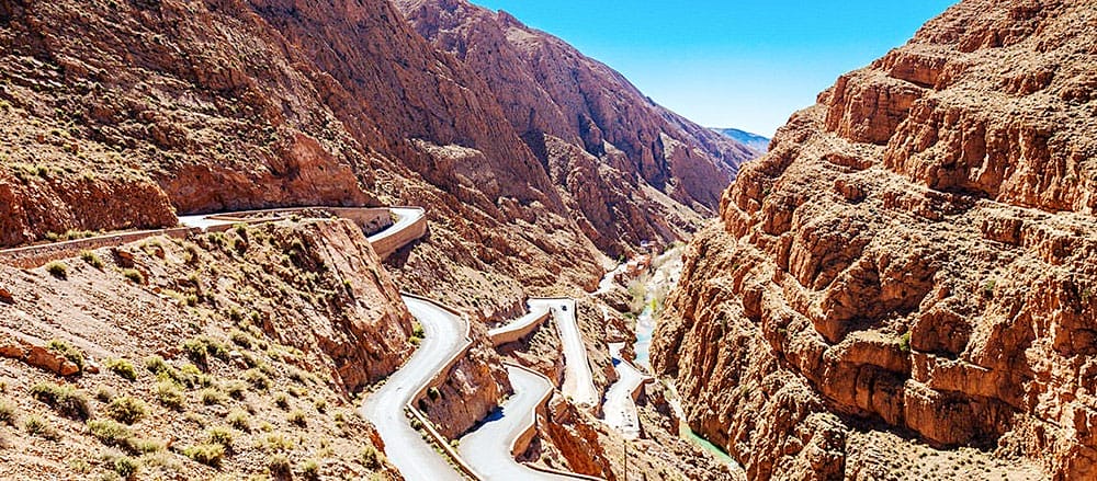 Una strada tortuosa in un canyon con Chefchaouen sullo sfondo.