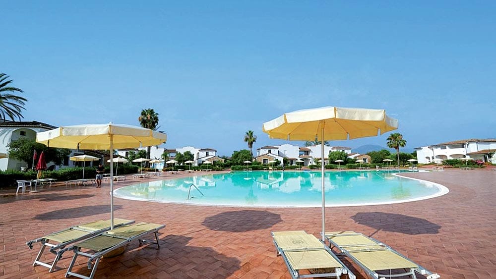 Una tranquilla piscina del resort MARINA TORRE NAVARRESE con lettini e ombrelloni in una giornata di sole.