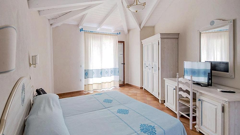 Camera da letto luminosa e ariosa con arredi bianchi e accenti blu Marina Torre Navarrese.