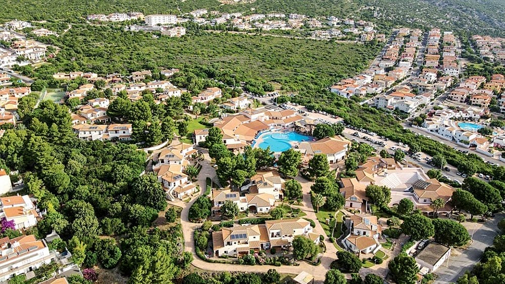 Veduta aerea del Club Esse Cala Gonone in Sardegna, con case uniformi e una piscina centrale immersa nel verde.