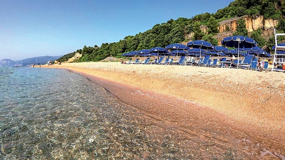 Una spiaggia in Sardegna con ombrelloni blu e acqua limpida.