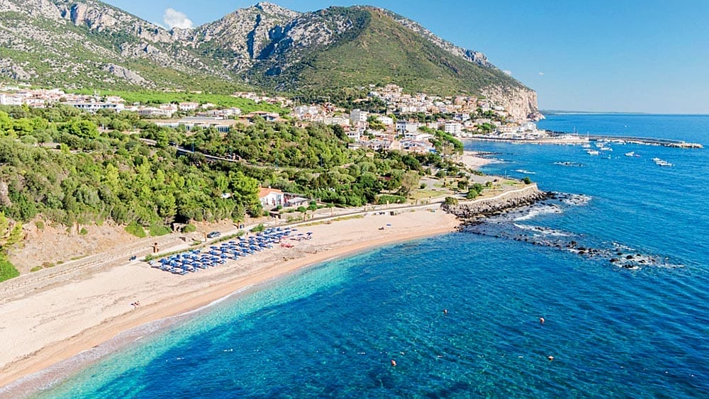 Veduta aerea del Club Esse Palmasera Resort con piscina vicino alla spiaggia e immerso nel verde in Sardegna.