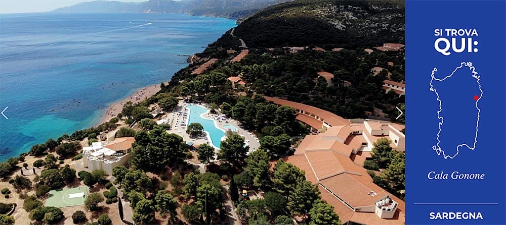 Veduta aerea del Club Esse Palmasera, una zona turistica costiera a Cala Gonone, Sardegna, con piscina, circondata da edifici dal tetto in terracotta e lussureggianti