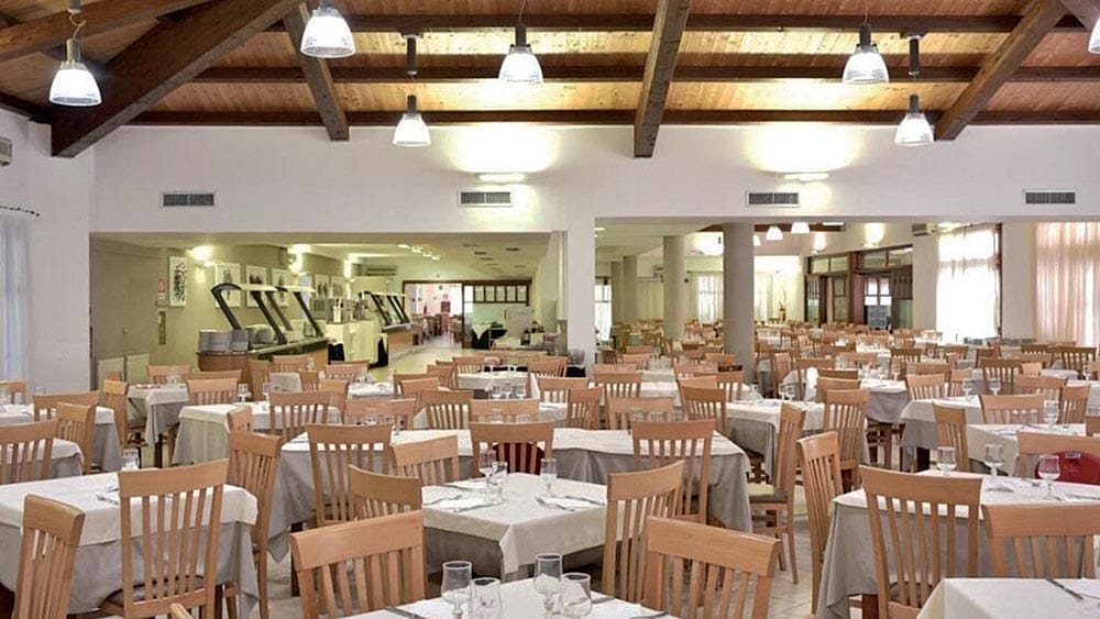 Interni spaziosi del ristorante Eurovillage Sardegna con tavoli ben disposti e soffitto con travi in legno.