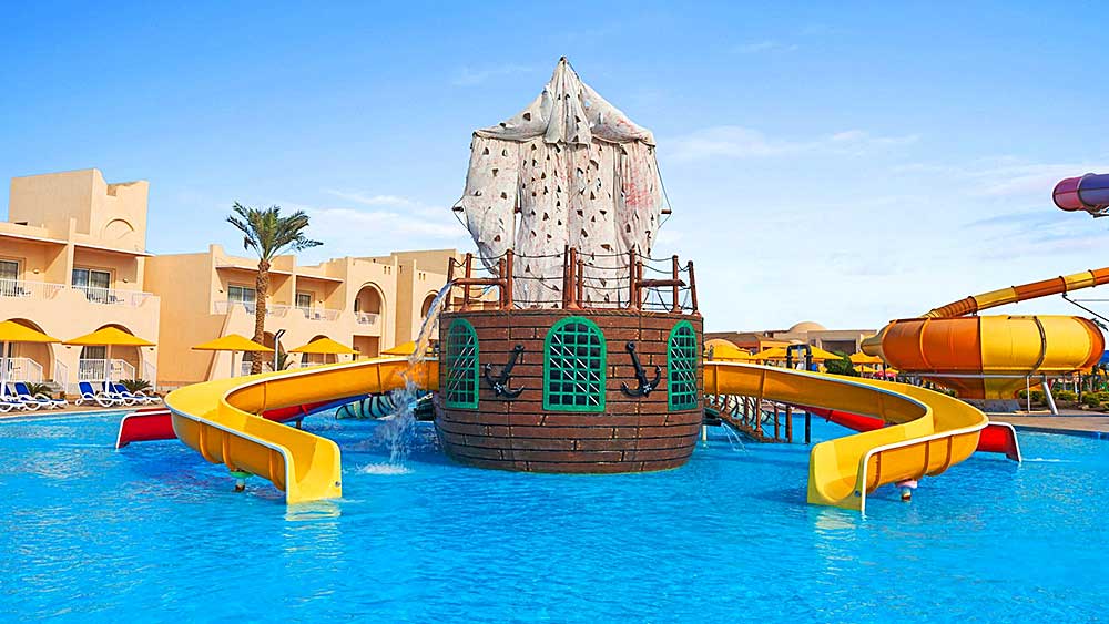 Un colorato parco acquatico caratterizzato da una nave pirata centrale con scivoli circostanti, situato nel Villaggio Mar Rosso.