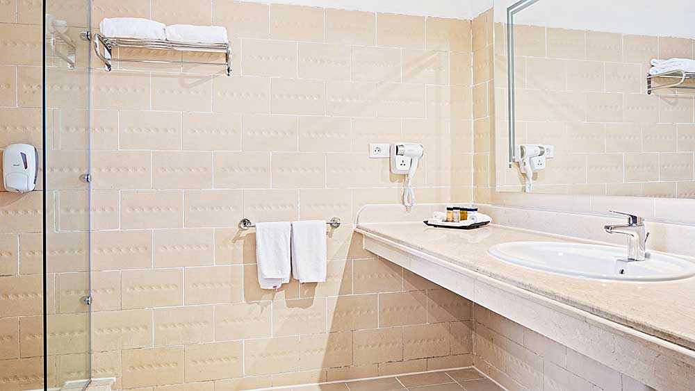 Un bagno pulito e semplice dell'hotel Villaggio Mar Rosso con doccia, lavandino e accessori.