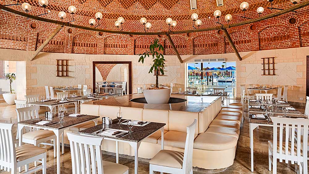 Interni eleganti del ristorante con soffitto a volte in mattoni e arredamento moderno, che ricorda l'ambientazione del Villaggio Mar Rosso.