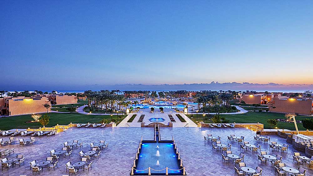 Un lussuoso resort Villaggio Mar Rosso con posti a sedere all'aperto, piscine e giardini curati al tramonto.