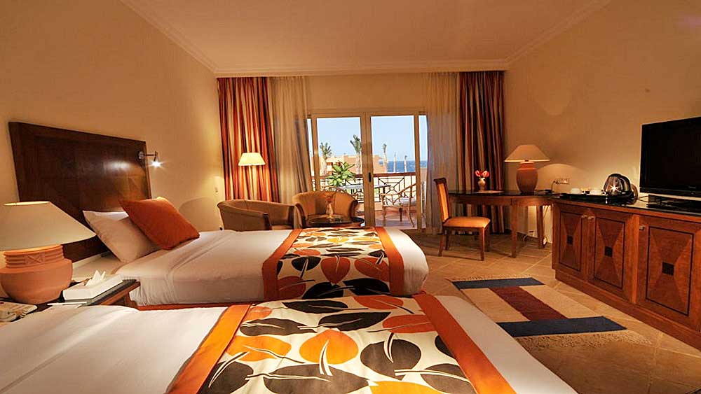 Una camera d'hotel accogliente e luminosa al Villaggio Marsa Alam con letti gemelli, balcone e comfort moderni.