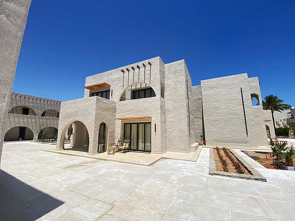 Moderna architettura del deserto caratterizzata da un edificio dalle linee pulite e dai toni neutri sotto un cielo azzurro e limpido, che esemplifica lo stile unico del villaggio Sharm El Sheikh.