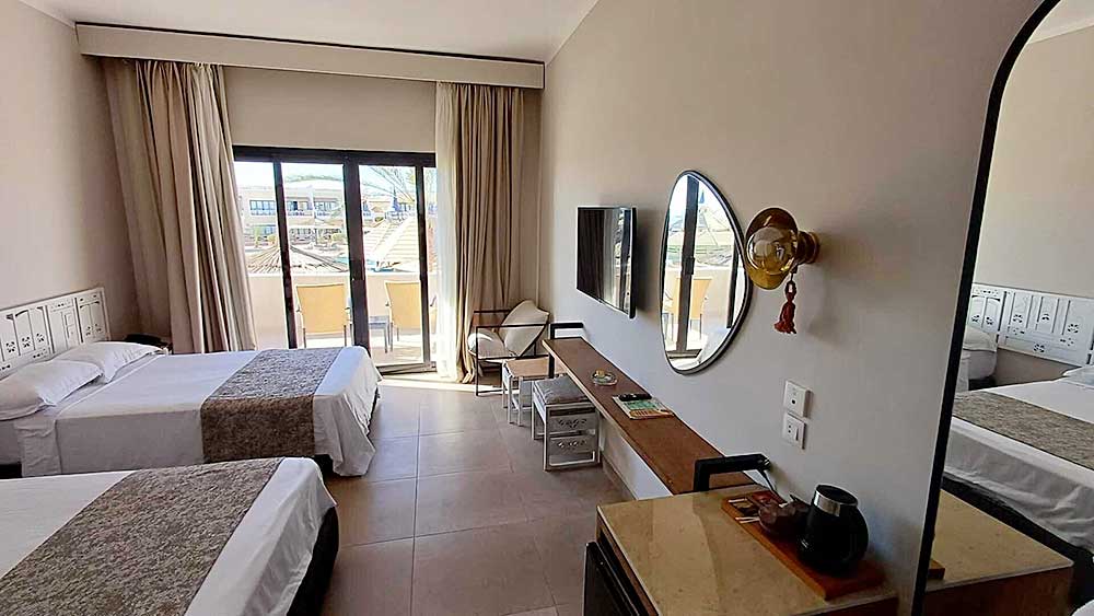 Una camera d'hotel luminosa e moderna al Villaggio Sharm El Sheikh con letti gemelli, balcone e mobili minimalisti.