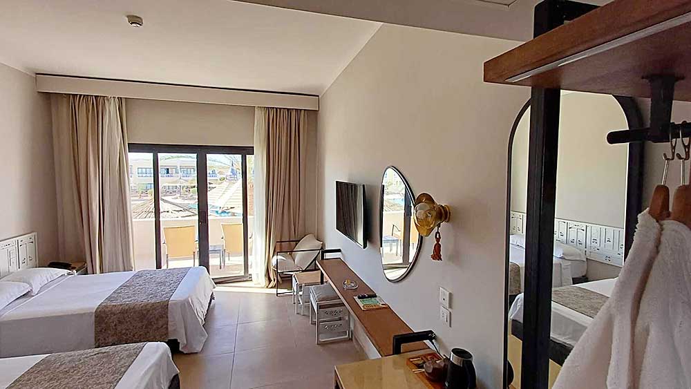 Interno moderno della camera d'albergo del Villaggio Sharm El Sheikh con letti gemelli, televisione e accesso al balcone.
